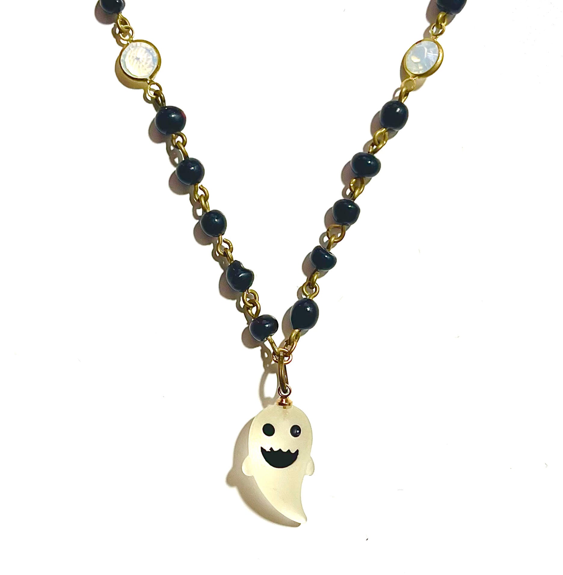 Black bead necklace with white ghost charm on white background.