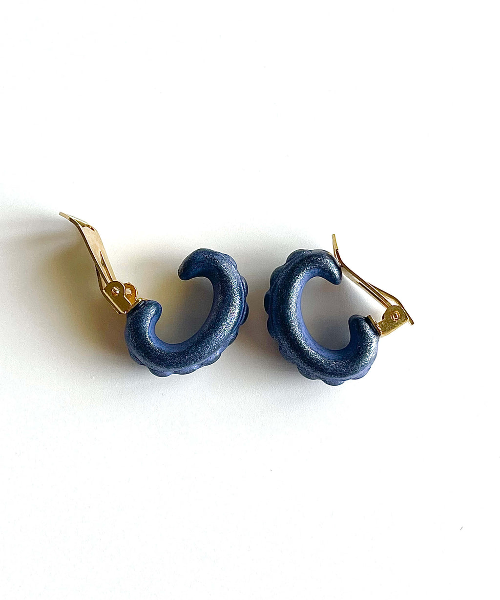 Yellow brass and purple acrylic clip-on earrings with dot details on white background