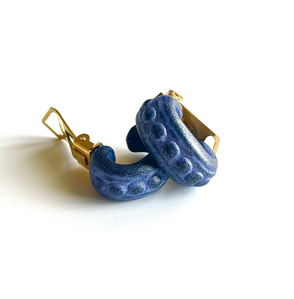 Yellow brass and purple acrylic clip-on earrings with dot details on white background